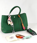 Green handbag with accessories on a white background