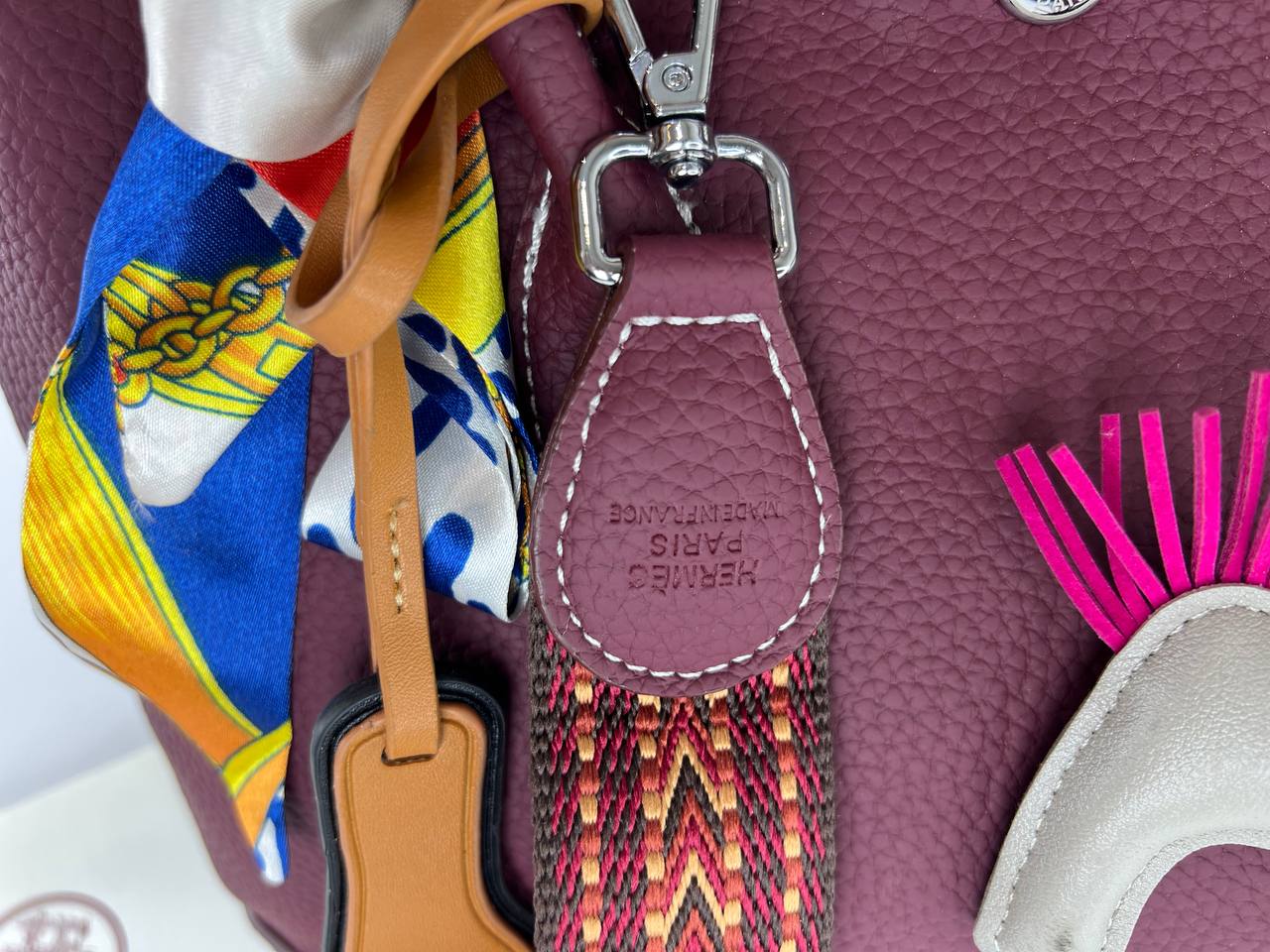 Close-up of a purple handbag with a colorful strap and decorative elements.