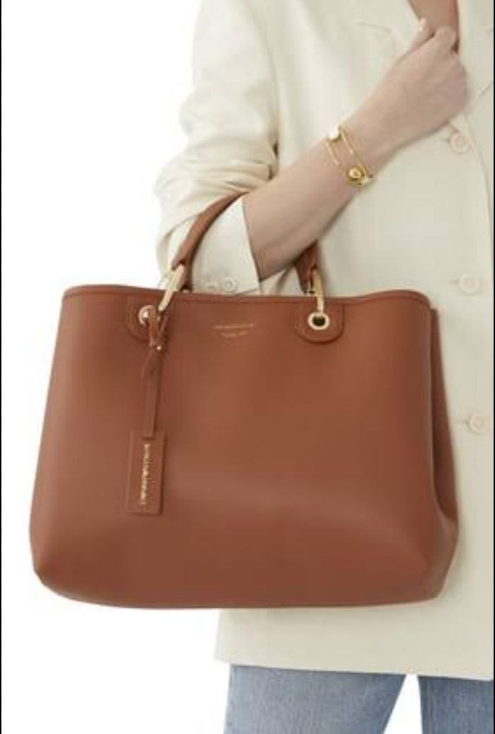 Brown handbag held by a person wearing a beige sweater.
