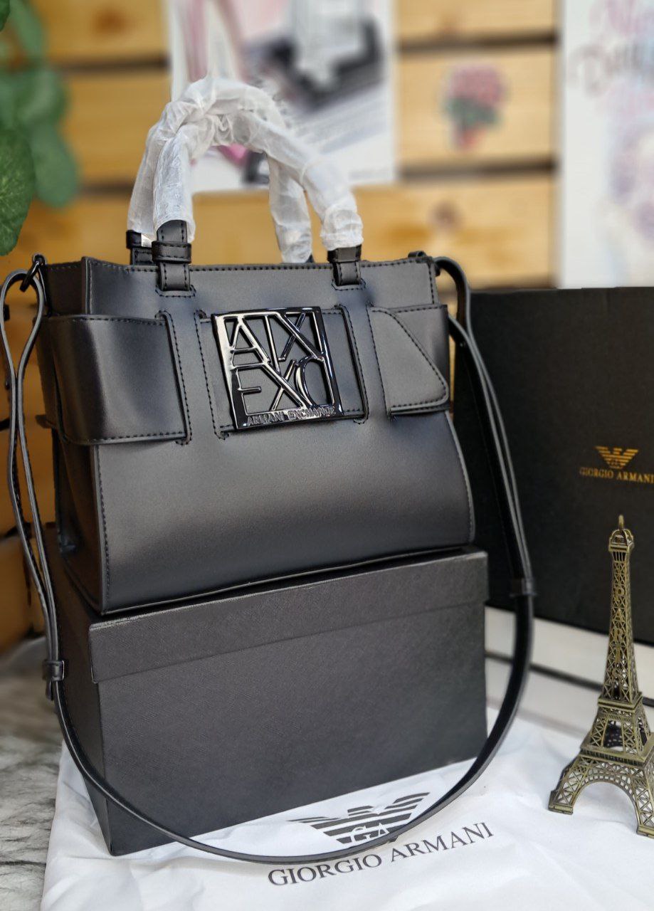 Black handbag with a brand logo on a white surface with a blurred background
