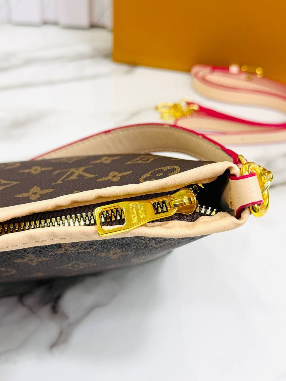 Louis Vuitton pouch with gold zipper on a marble surface