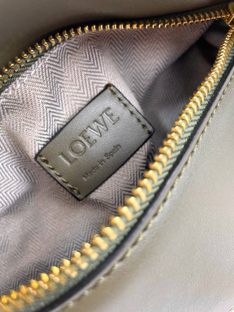 Loewe logo on a textured fabric surface with gold stitching