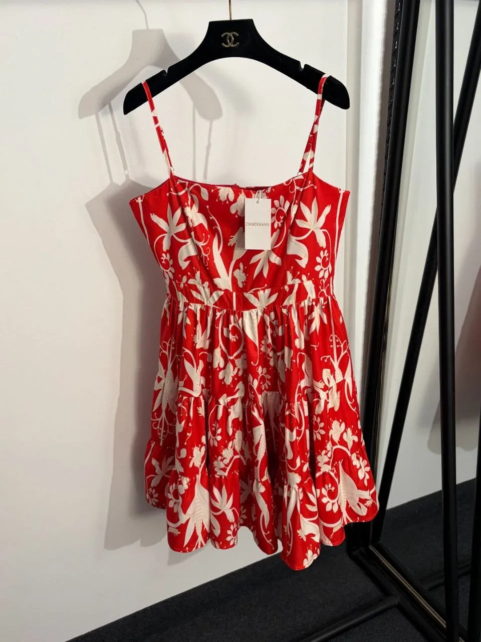 Red floral dress on a hanger against a white wall