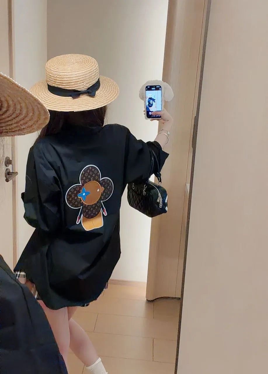 Person wearing a black sweatshirt with a graphic design, straw hat, and white socks in front of a mirror.