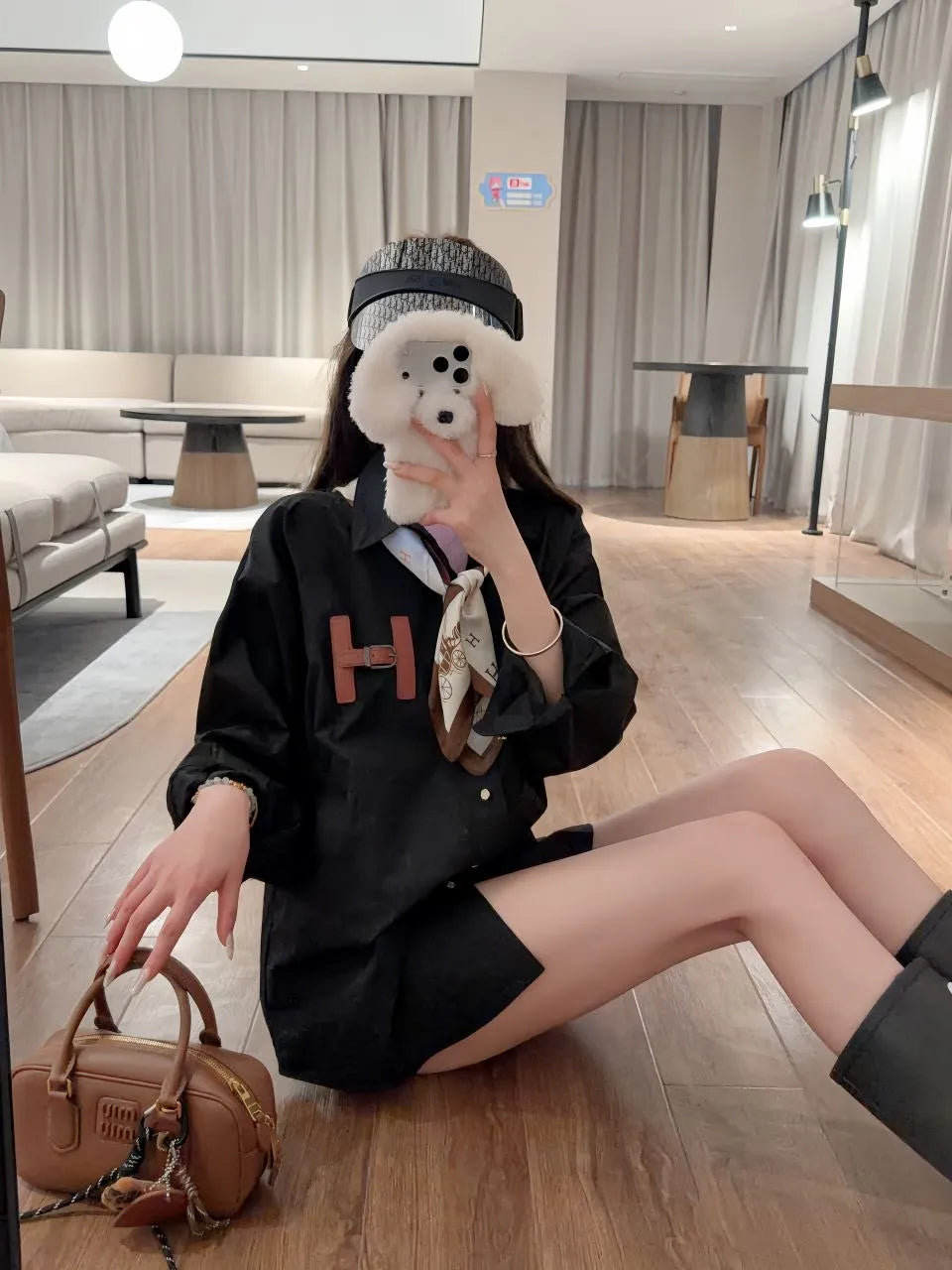 Person sitting on the floor in a modern living room taking a mirror selfie.