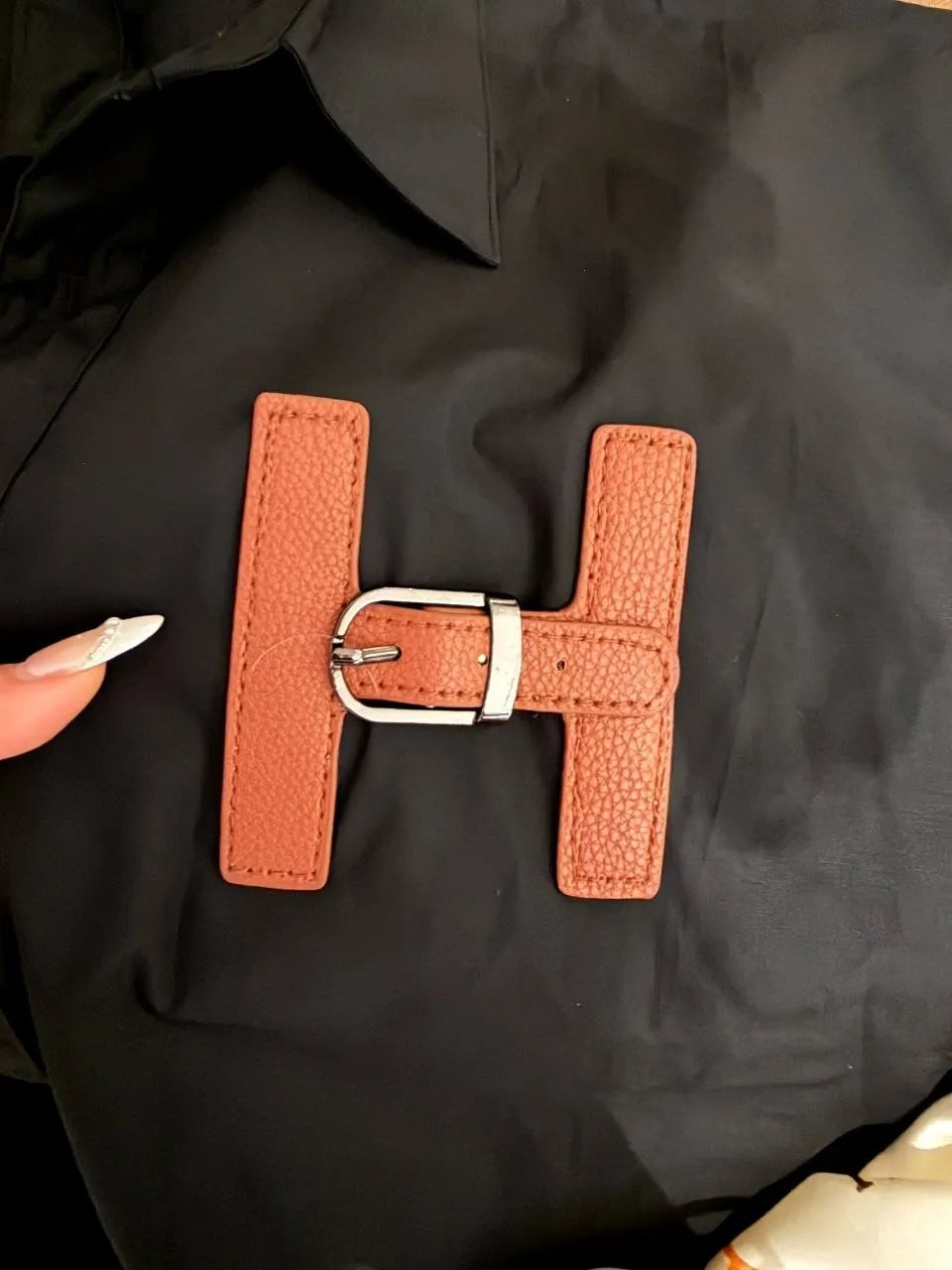 Brown leather patch with a silver buckle on a black surface