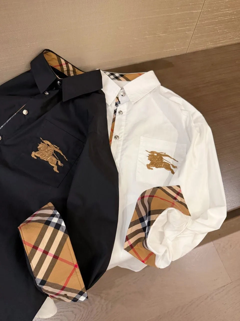 Black and white Burberry shirts with checkered patterns on a wooden surface