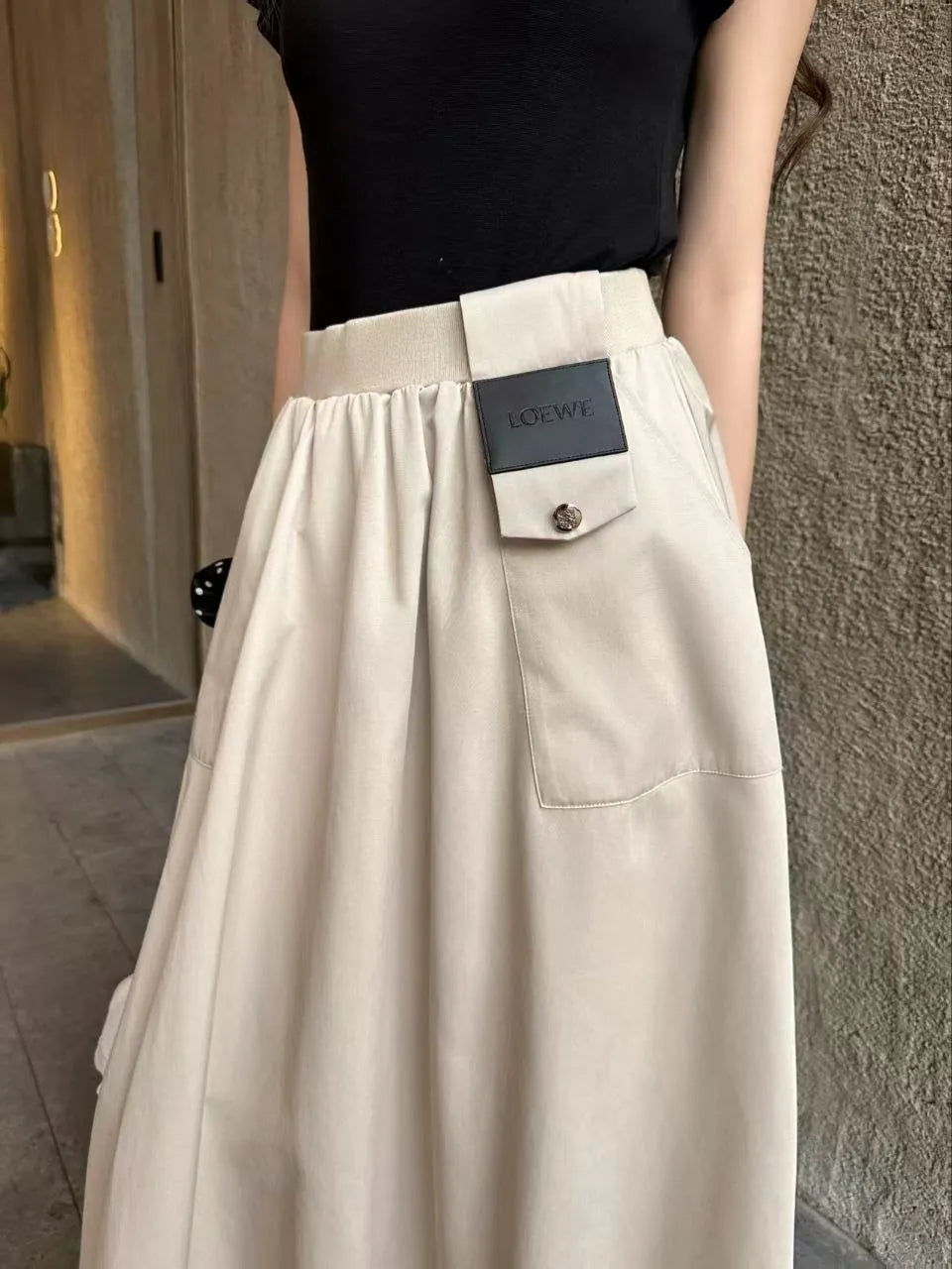 Beige skirt with a brand label worn by a person, against a neutral background