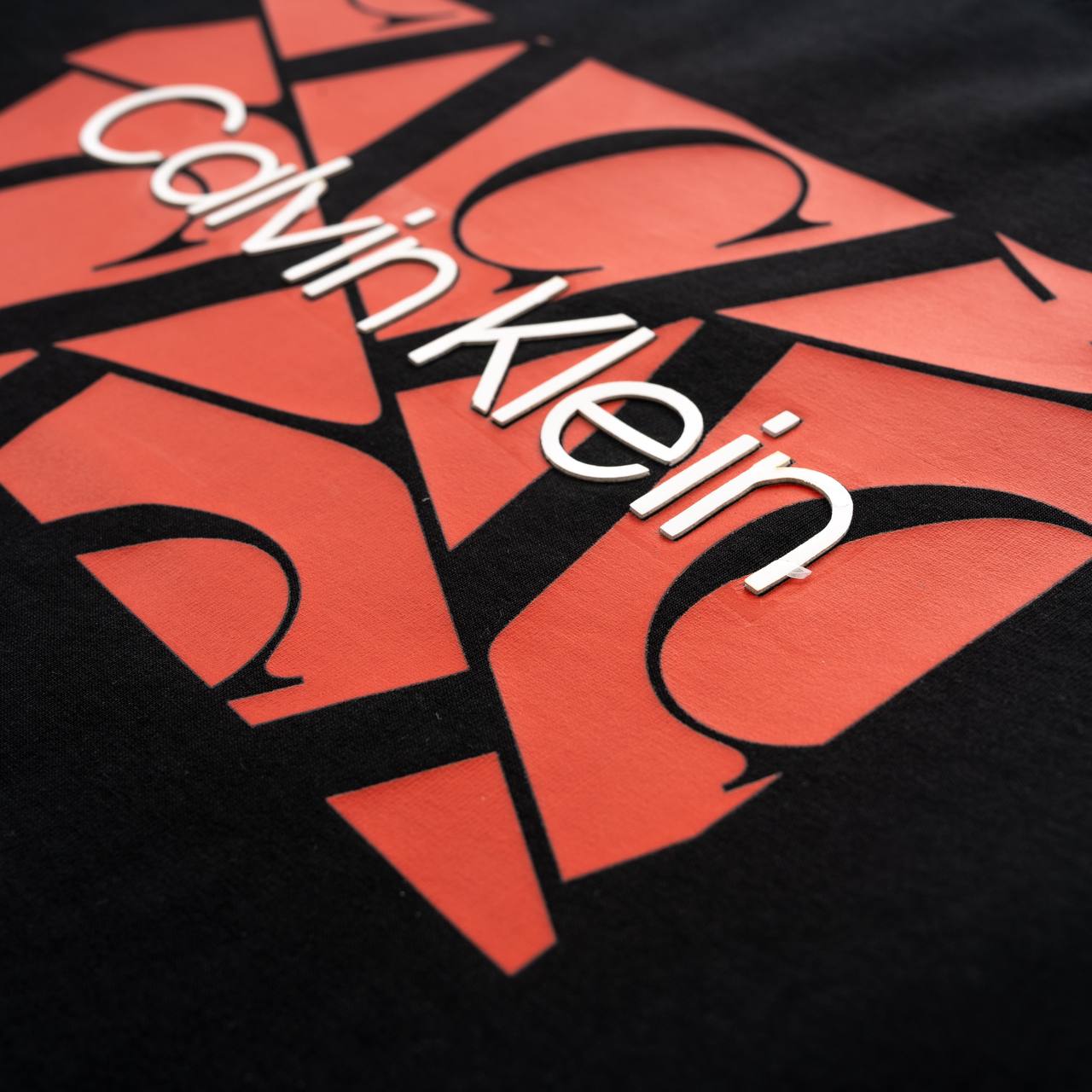 Calvin Klein logo on a black and red patterned background
