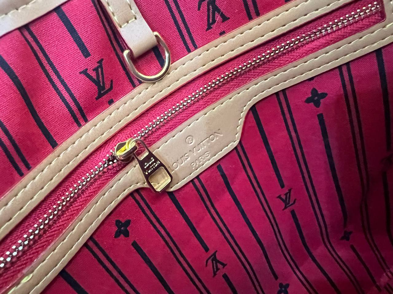 Close-up of a pink Louis Vuitton bag with a gold zipper and logo.