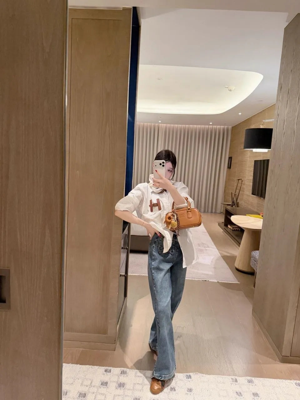 Person taking a mirror selfie in a modern living room.