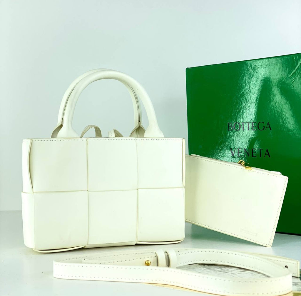 White handbag with matching wallet and green Bottega Veneta box on a light gray background