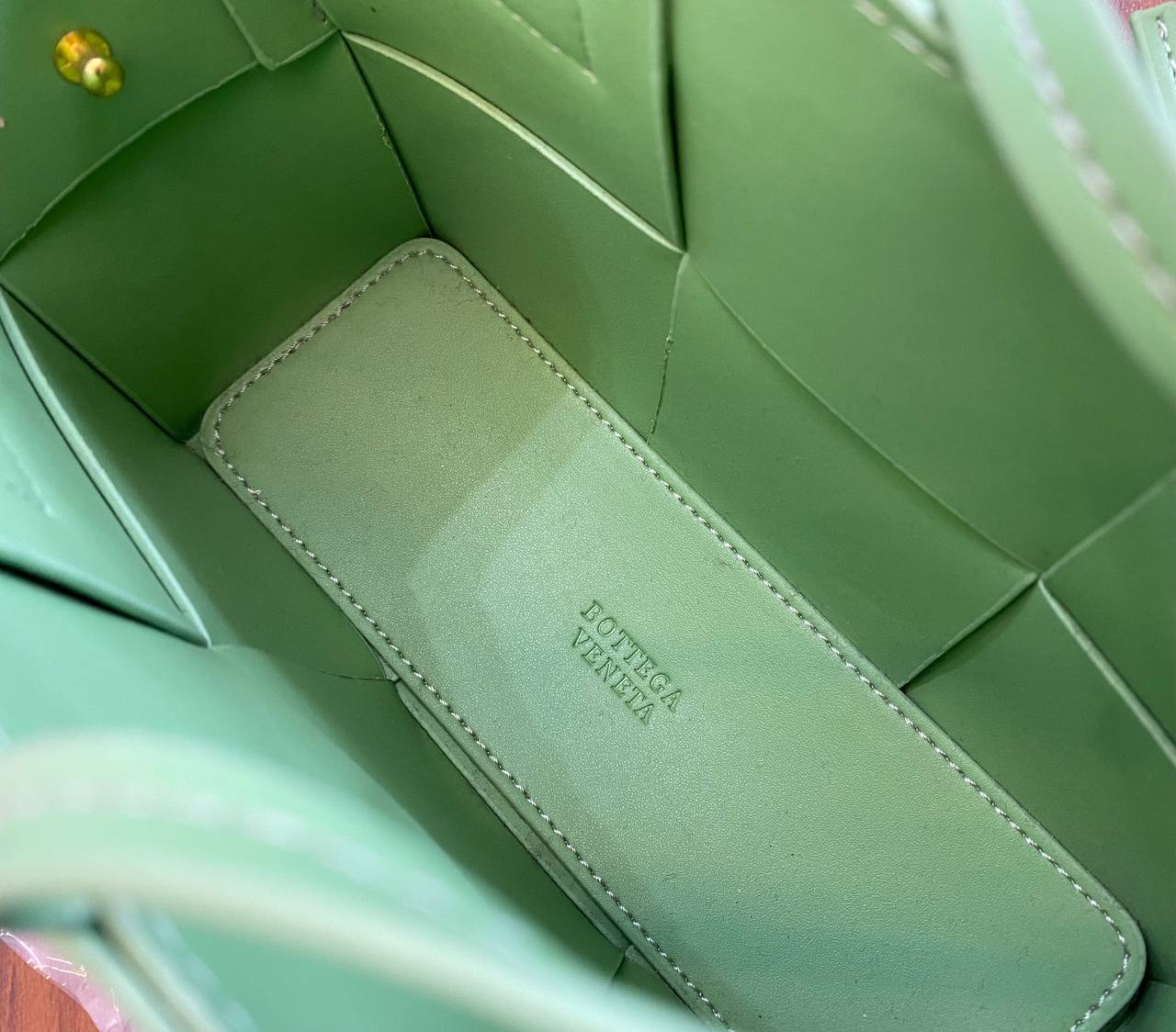 Green leather wallet with 'Bottega Veneta' branding inside a green handbag.