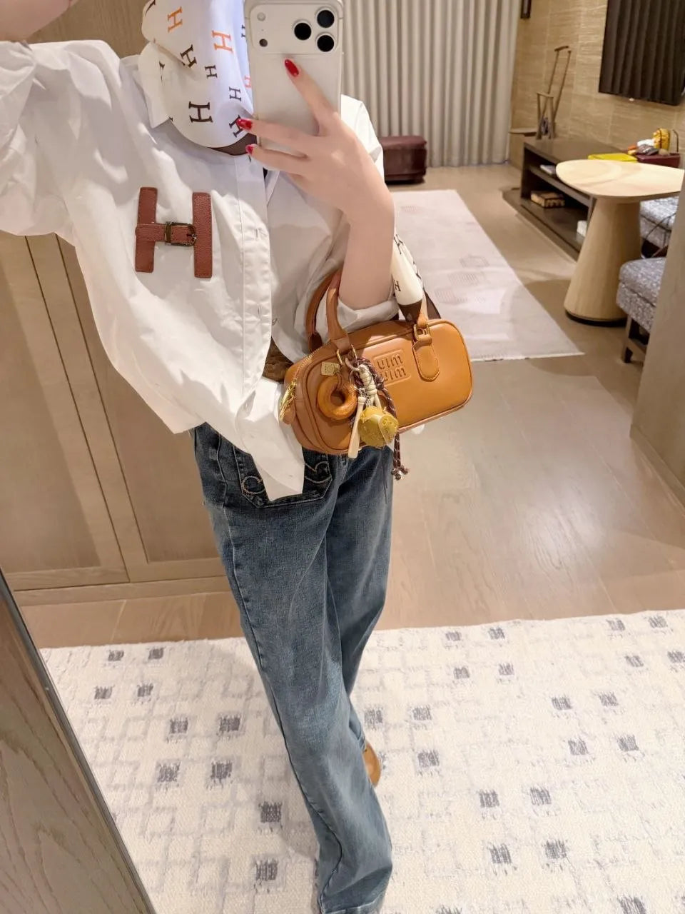 Person taking a mirror selfie wearing a white shirt, blue jeans, and holding a yellow handbag.