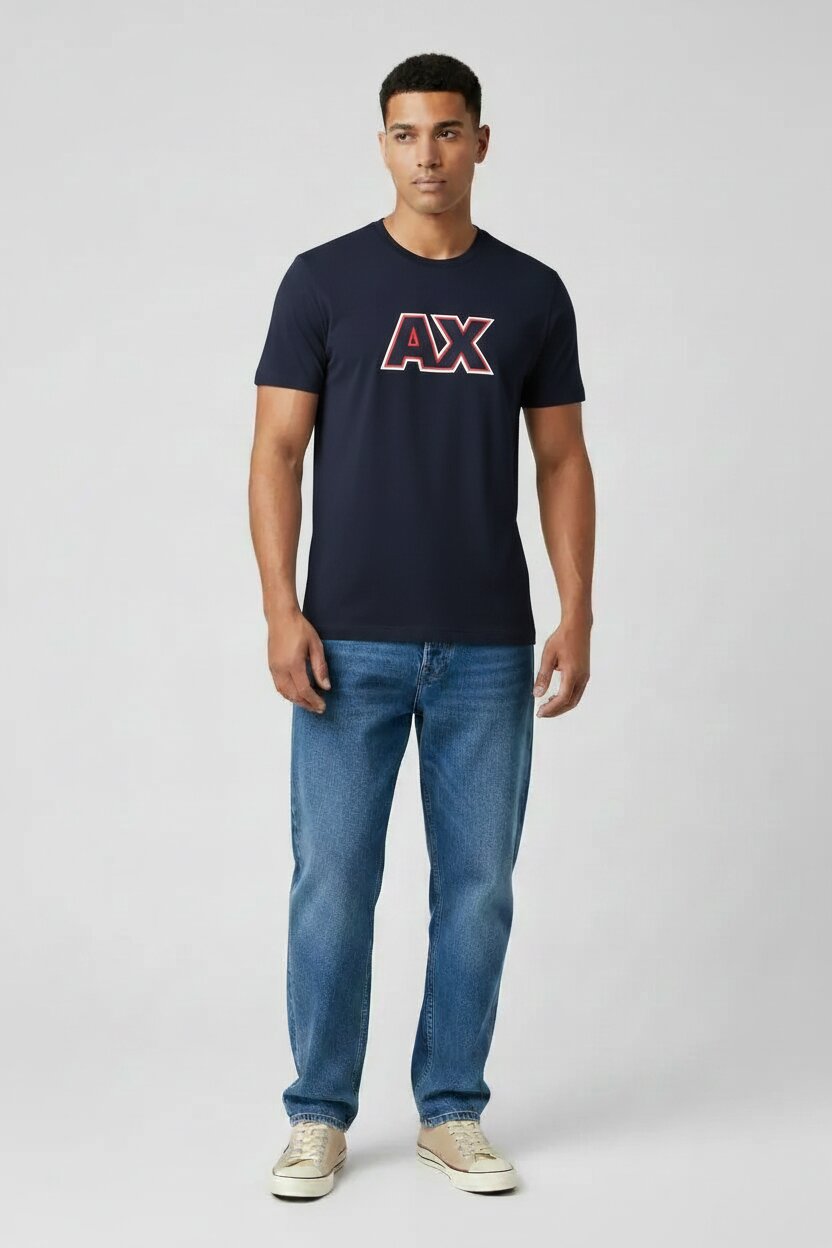Man wearing a navy t-shirt with a logo and blue jeans on a light gray background