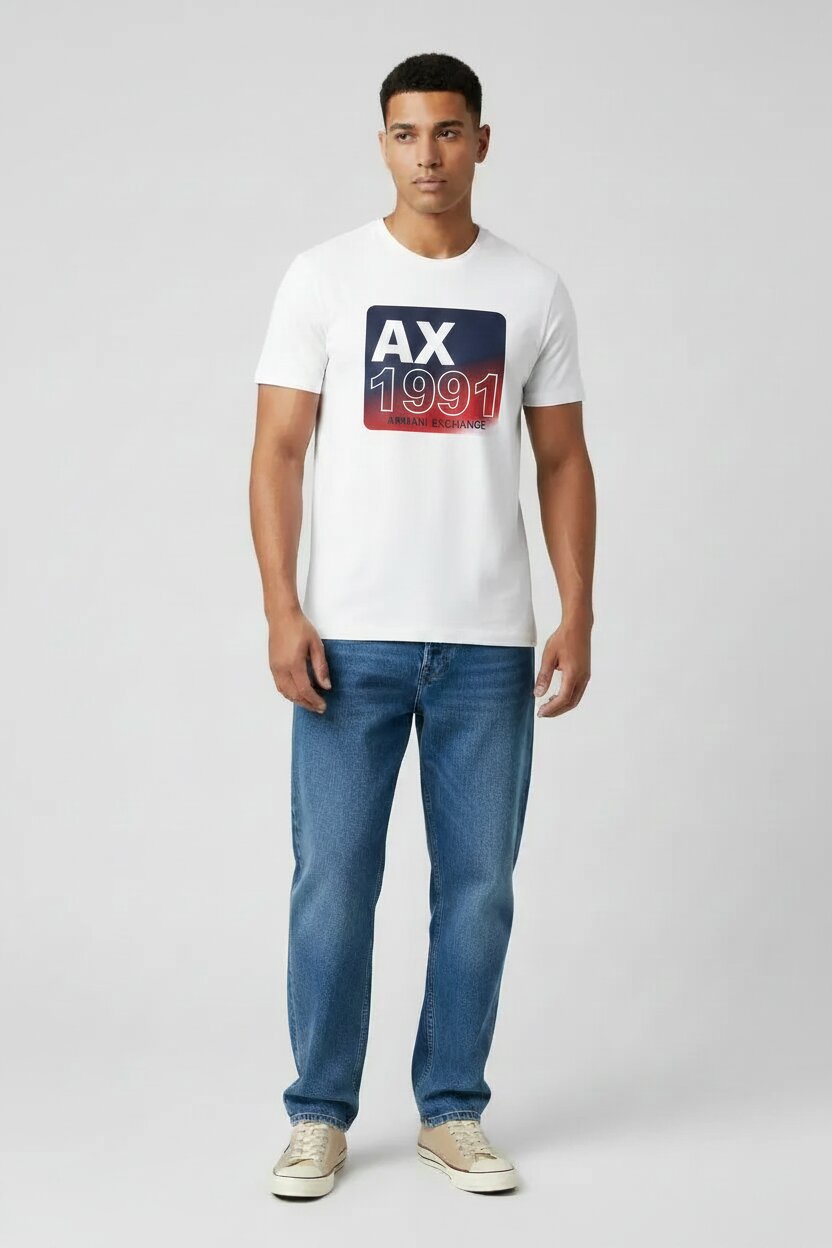 Armani Exchange White AX 1991 Graphic T-Shirt on Male Model - Medium Blue Straight Leg Jeans and Beige Sneakers - Light Gray Studio Background - Full Body Shot