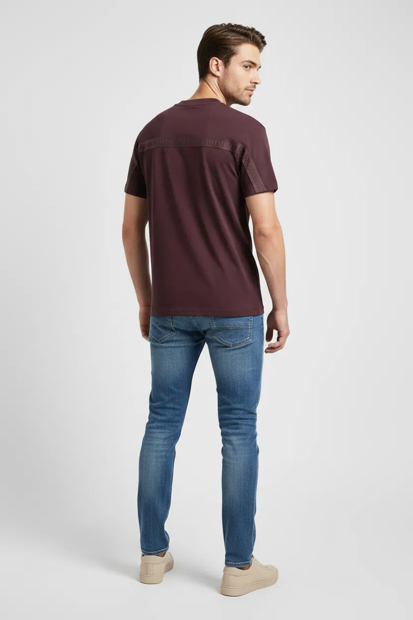 Man wearing a maroon t-shirt and blue jeans on a white background