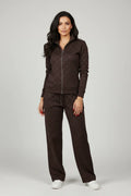 Female model wearing Calvin Klein CK monogram dark brown tracksuit set full body white sneakers gold accessories gray studio background