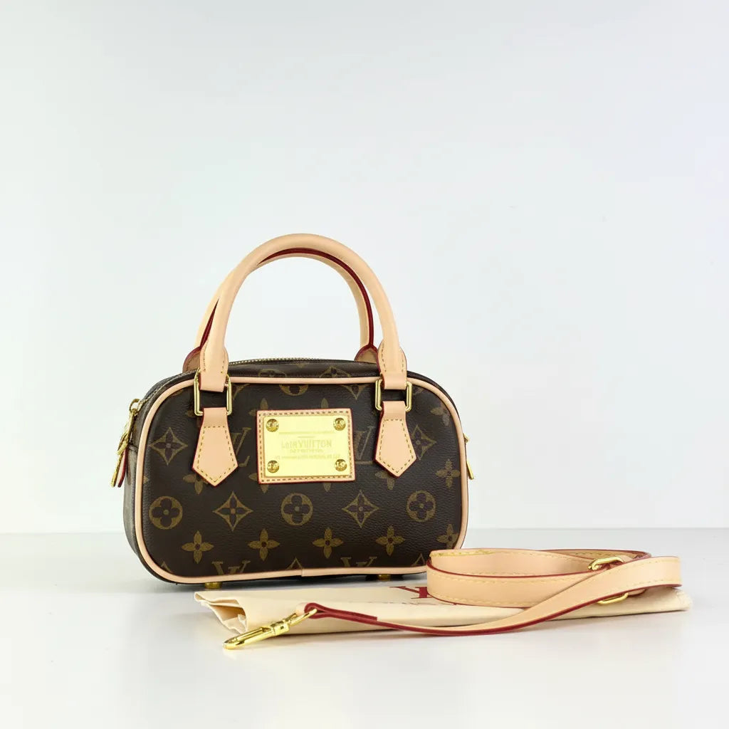 Designer handbag with monogram pattern and beige accents on a light gray background