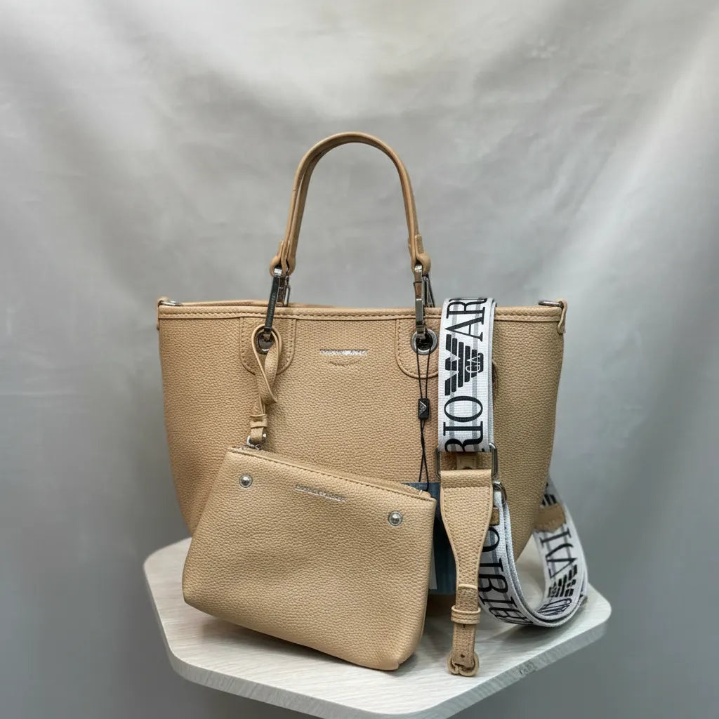 Beige handbag with matching pouch and branded strap on a gray background