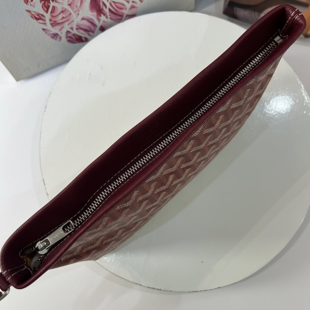 Goyard Senat Clutch Wristlet Bag in Burgundy - Close-up Top Zipper and Pebbled Leather Trim Detail - Light Gray Background