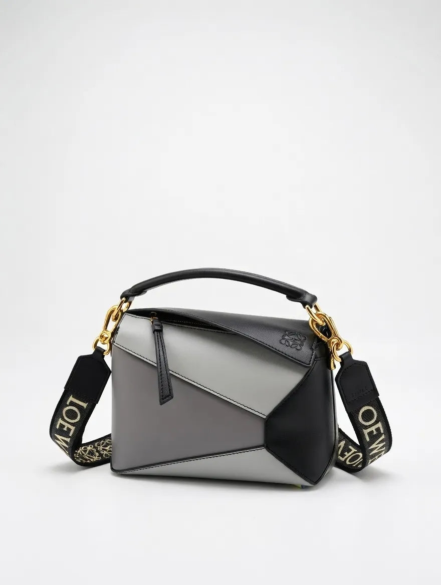 Gray and black handbag with gold accents on a light gray background