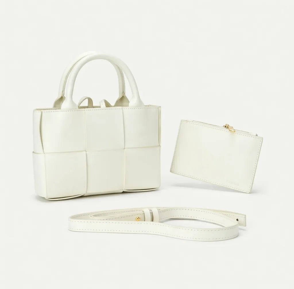 White handbag with matching pouch and strap on a light gray background