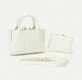 White handbag with matching pouch and strap on a light gray background