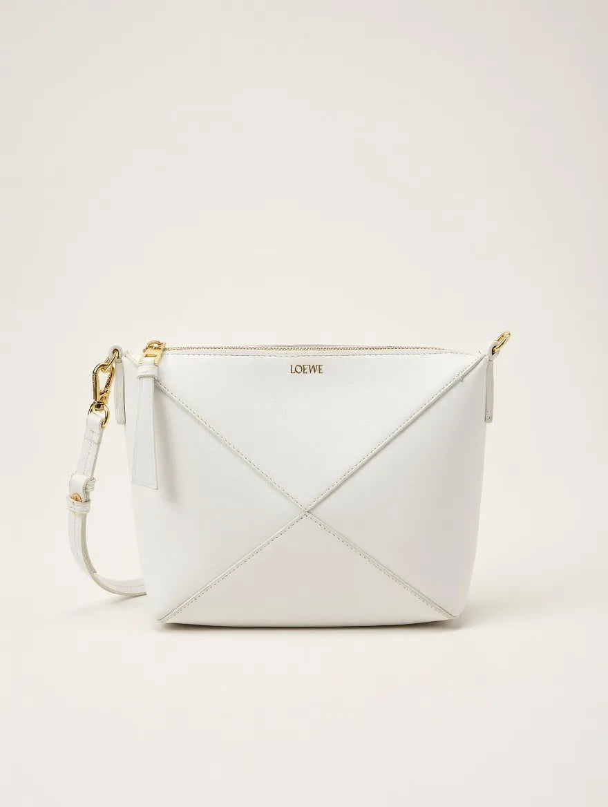White handbag with gold accents on a light beige background