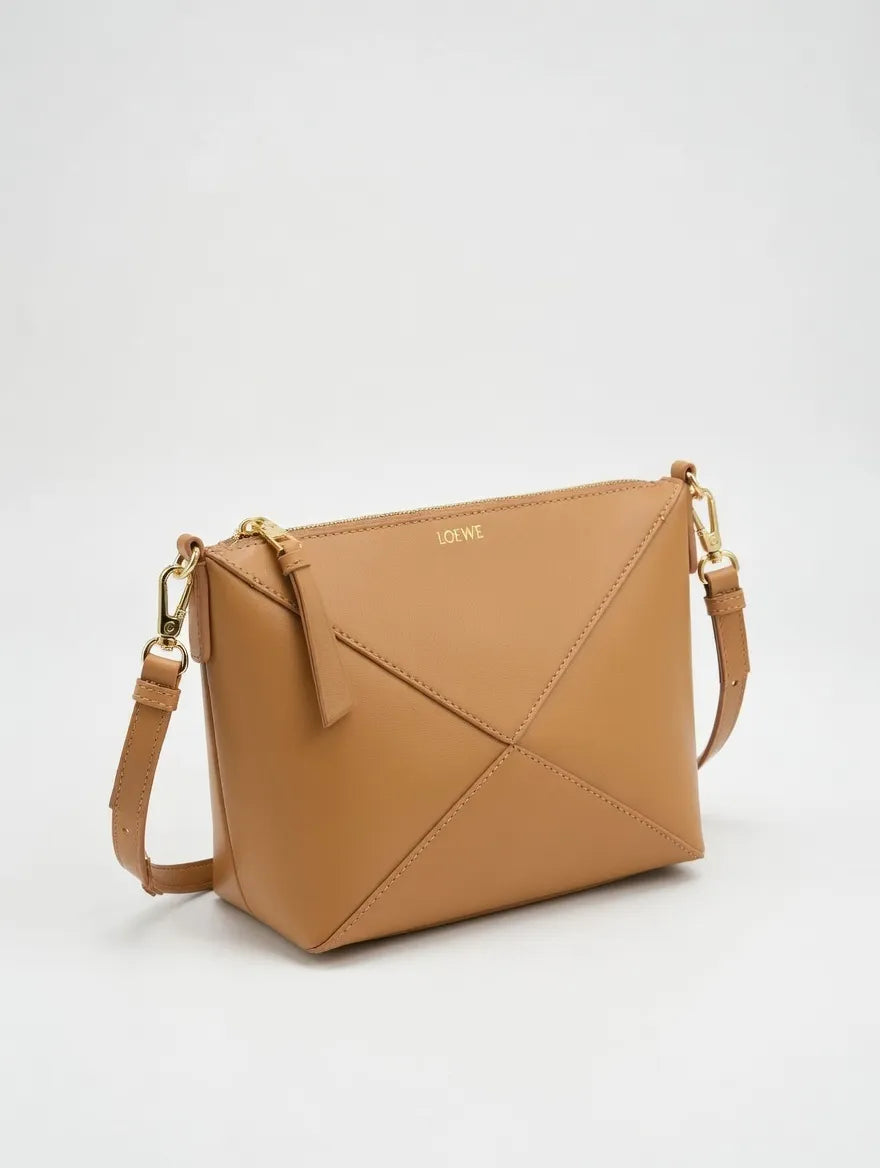  Lowe Tan handbag with gold accents on a light gray background