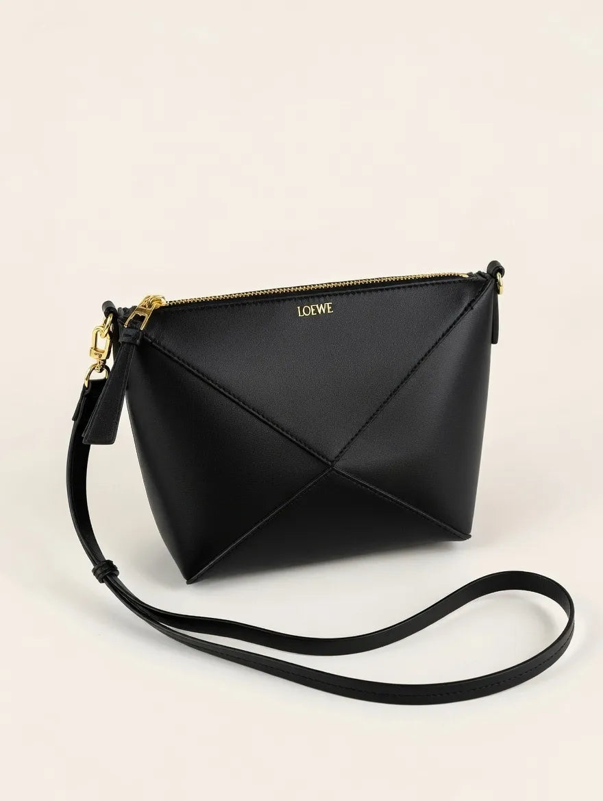 Black handbag with a strap on a light beige background
