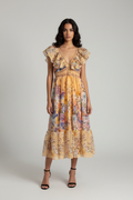 Female model wearing Floral Ruffle V-Neck Midi Dress in golden peach with colorful floral print on light gray studio background