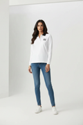 Female model wearing Miu Miu white long sleeve polo shirt black collar MIU MIU logo blue slim jeans white sneakers gray studio background