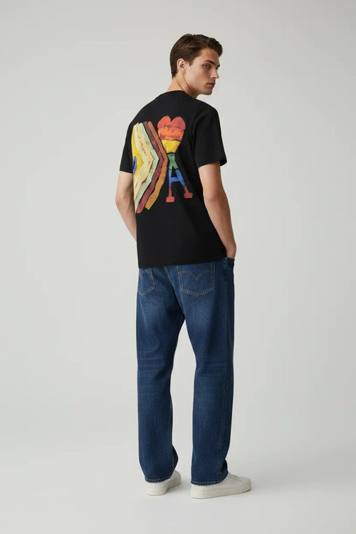 Man wearing a black t-shirt with a colorful graphic design on the back, standing against a plain background.