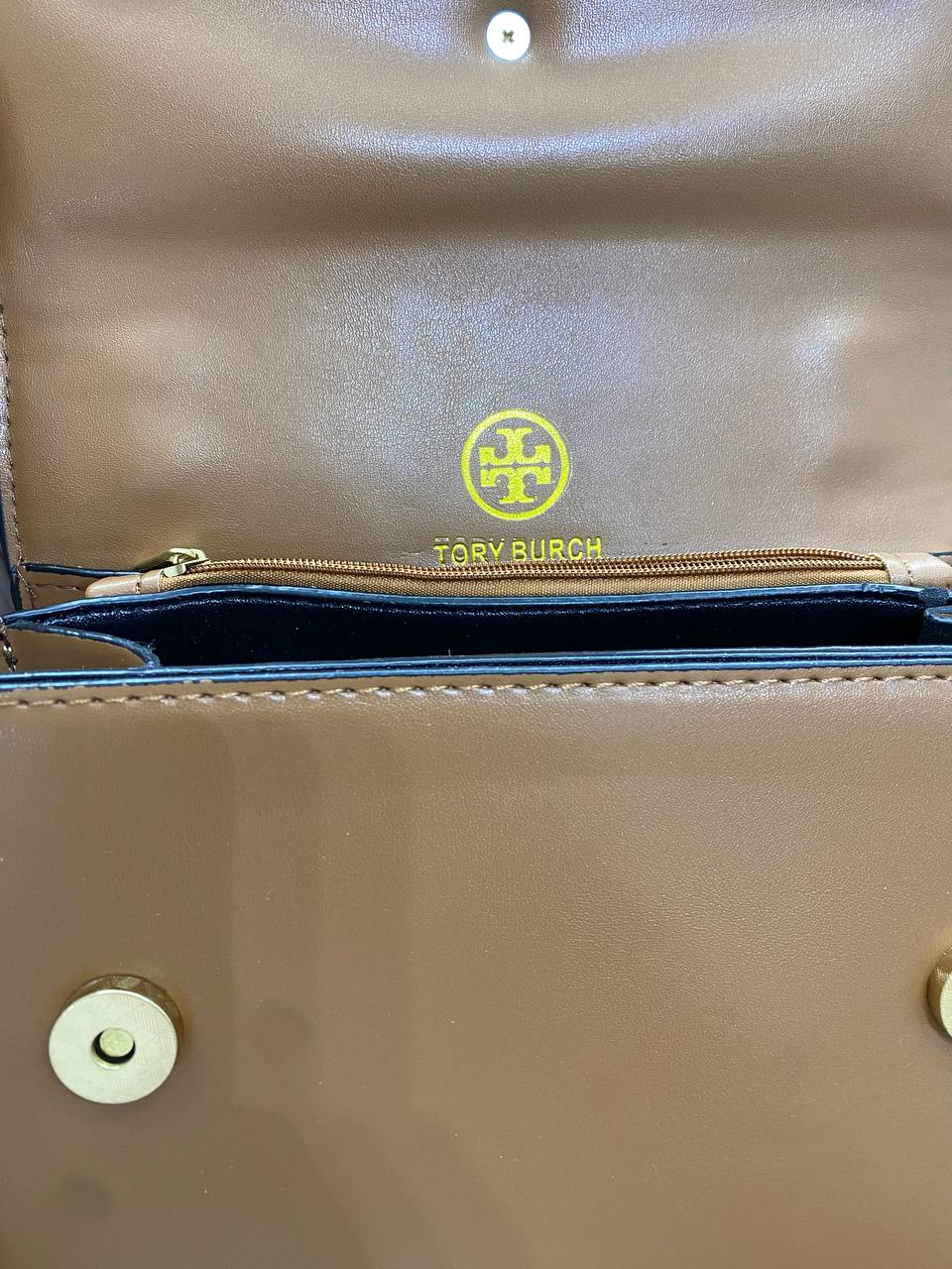Beige handbag with gold zipper and visible brand logo