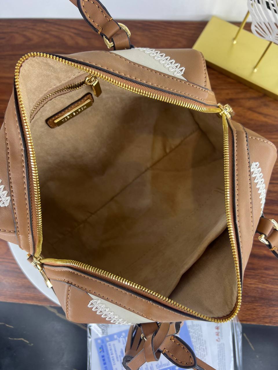 Brown leather bag with gold zipper on a wooden surface
