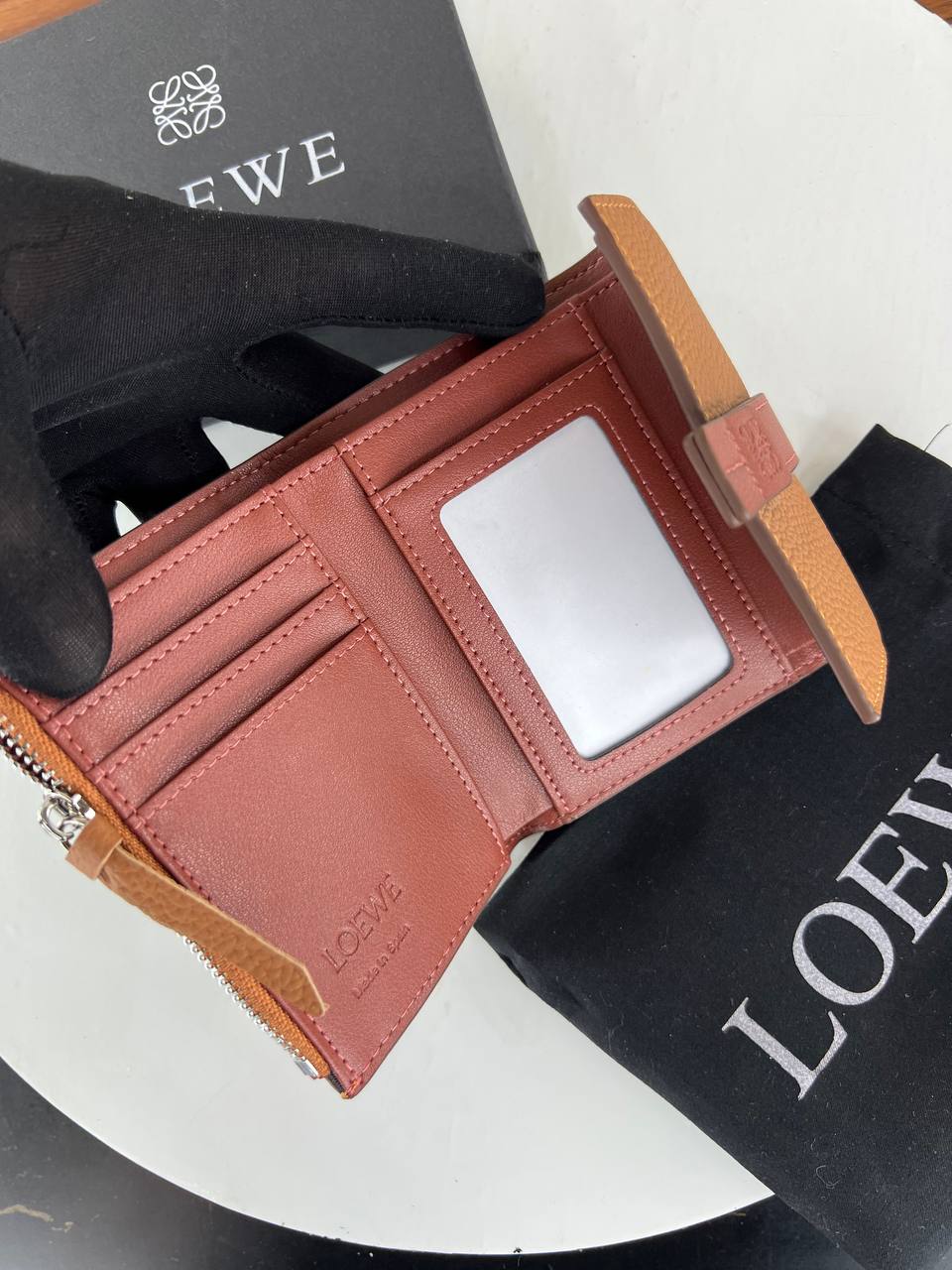 Brown leather wallet with card slots on a white surface with Loewe branding.