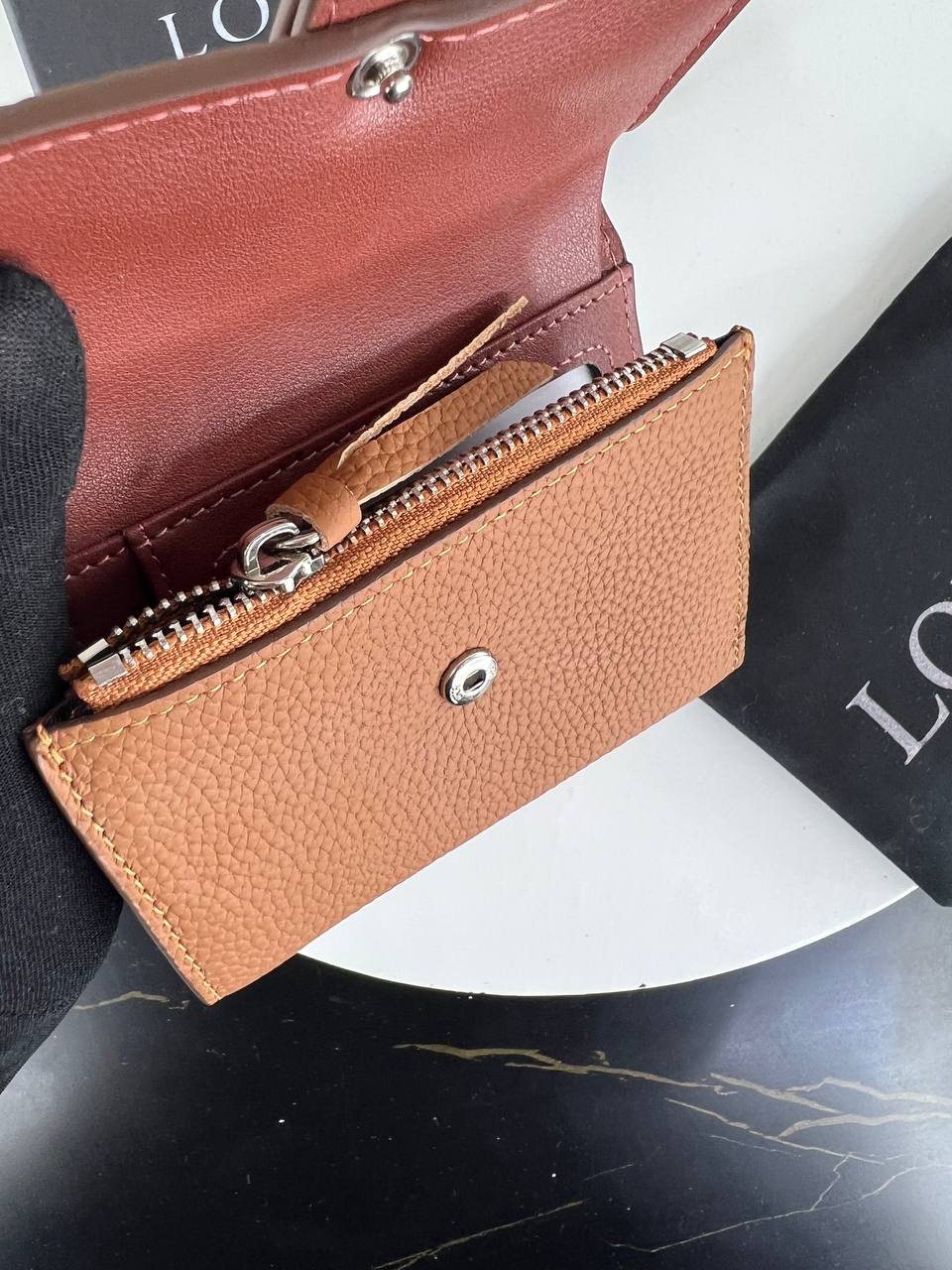 Brown leather wallet with zipper on a black and white background
