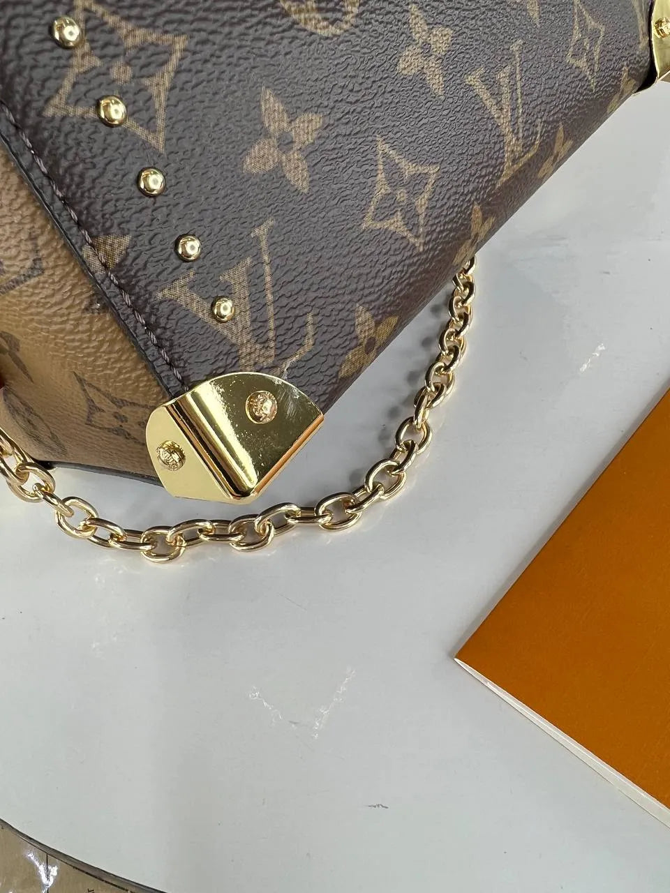 Louis Vuitton handbag with gold chain and hardware on a white background