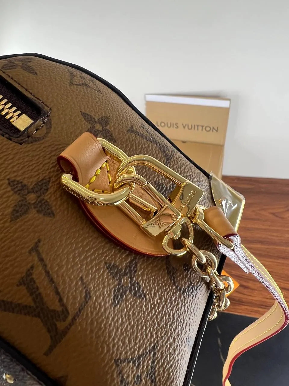 Louis Vuitton handbag with gold chain detail on a wooden surface