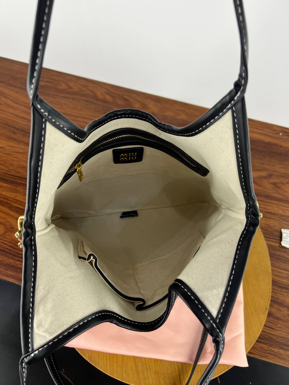 Black handbag with beige interior on a wooden surface