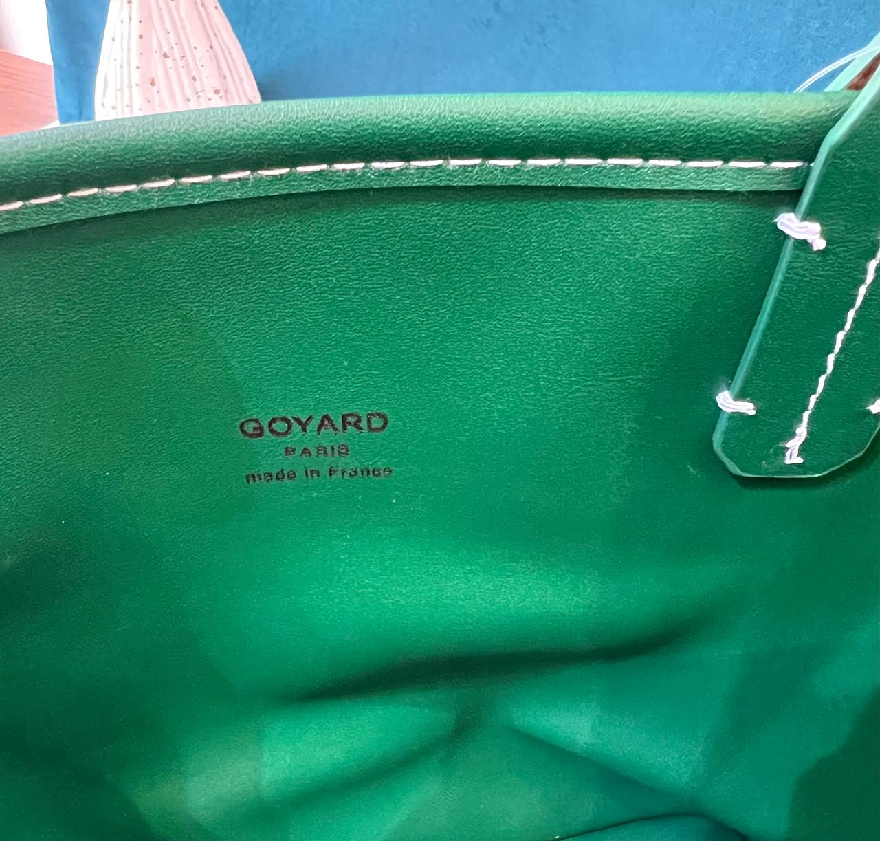 Close-up of a green Goyard bag with visible branding.