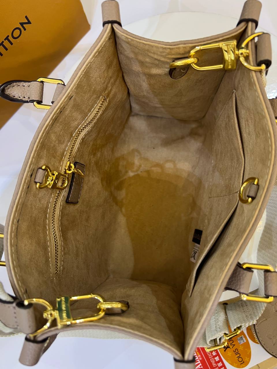 Beige handbag with gold hardware on a white background