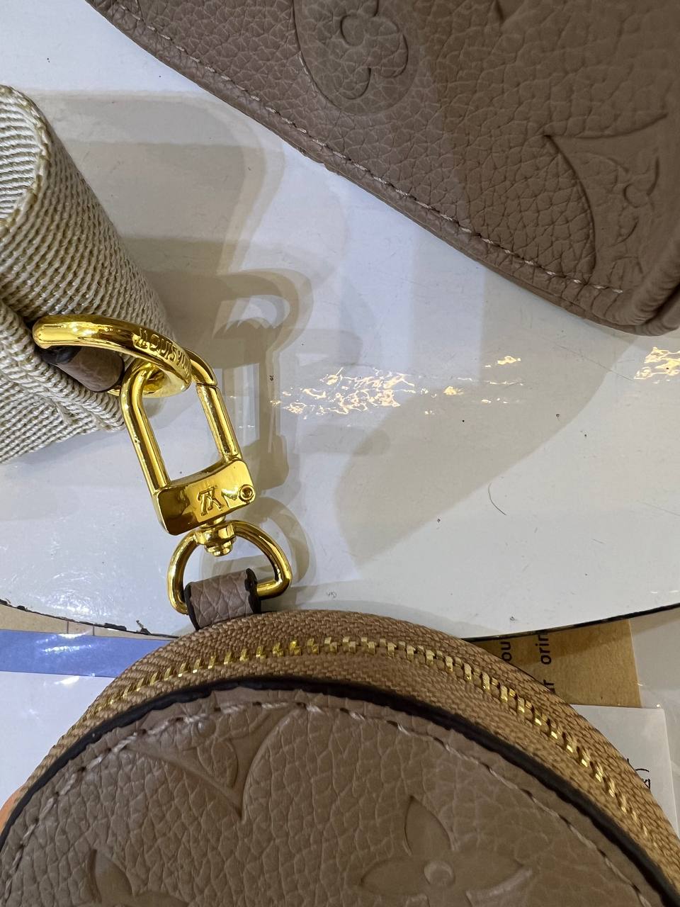 Brown leather coin purse with gold clasp on a reflective surface