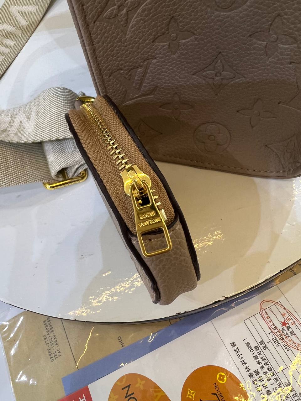 Brown leather wallet with gold zipper on a reflective surface