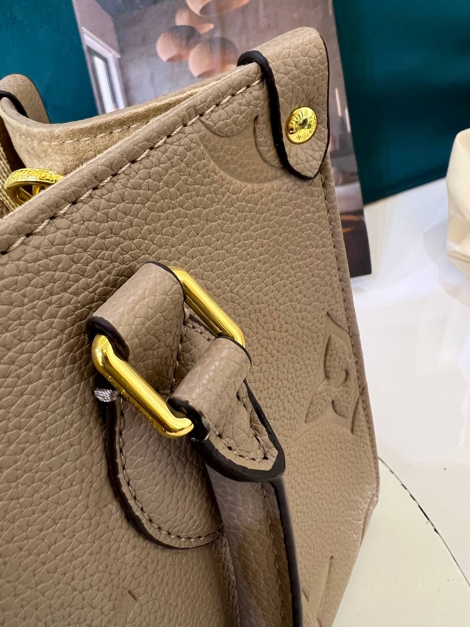 Close-up of a beige leather handbag with gold hardware on a blurred background