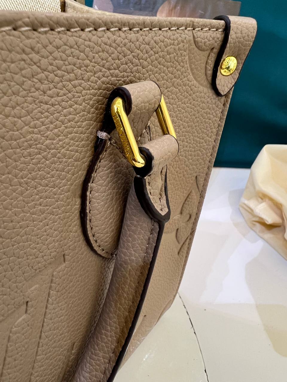 Close-up of a beige handbag with gold hardware on a blurred background