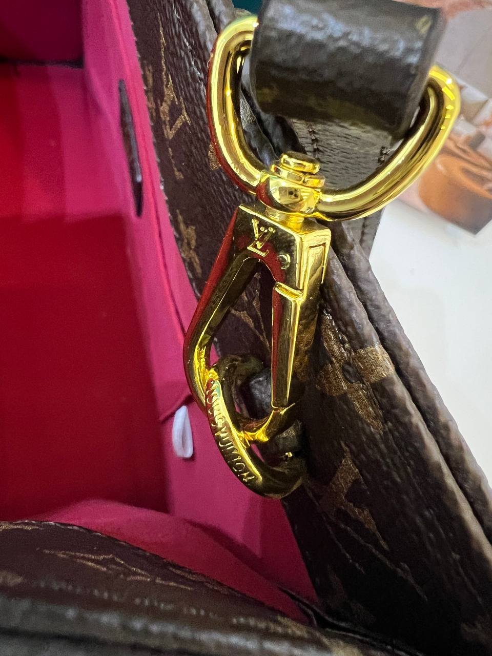 Gold hardware on a brown leather bag with visible brand logo.