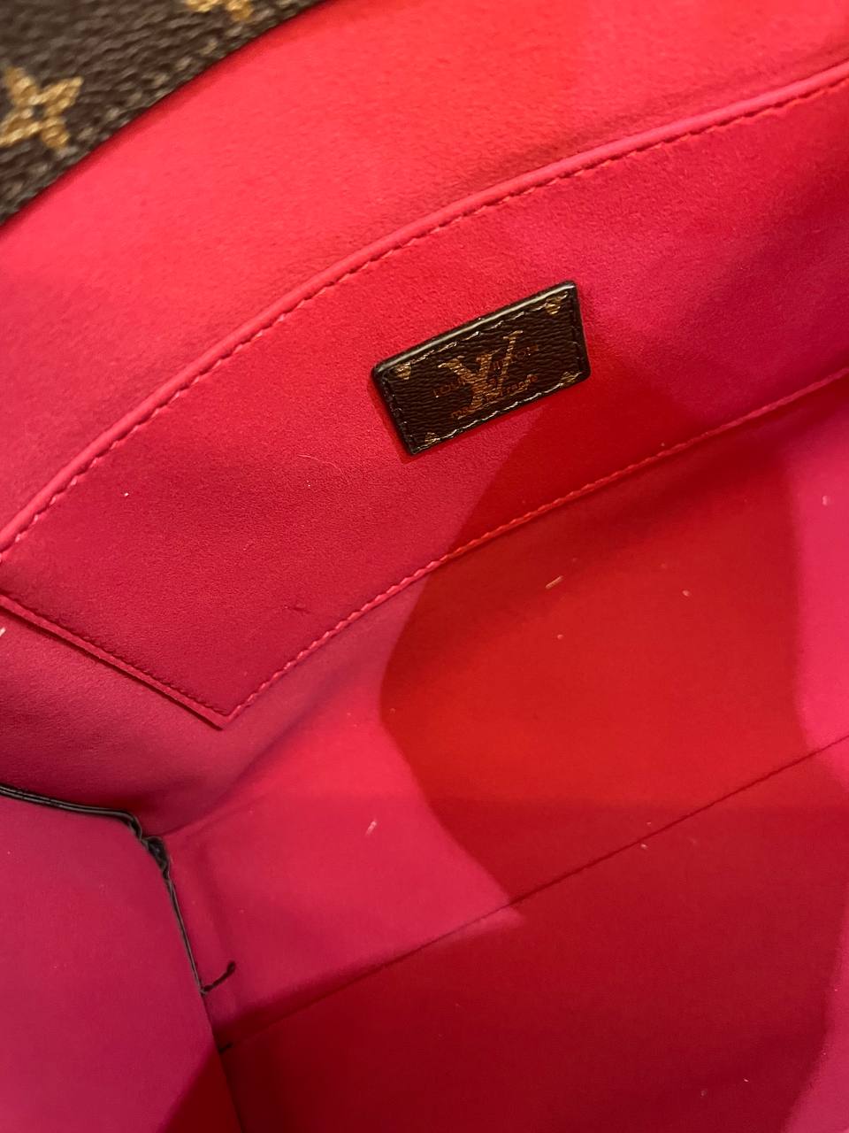 Close-up of a red Louis Vuitton handbag with a visible logo.