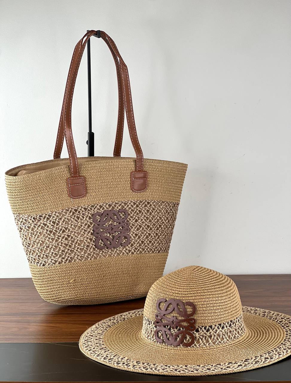 Woven straw bag and hat set on a wooden surface with a white background